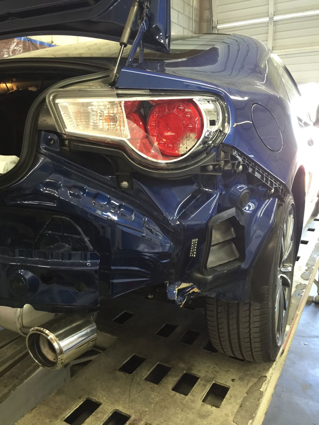 Subaru BRZ with damaged rear bumper and taillight before repair